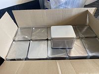 Cardboard box containing 11 silver rectangular metal boxes with mesh sides and solid lids.