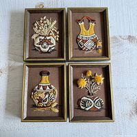 Four framed vintage crewel embroidery pictures of Native American Hopi Indian vases arranged together on a white textured surface.