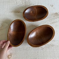 Top-down photo of all three wooden oval bowls showing their medium brown color and polished finish.