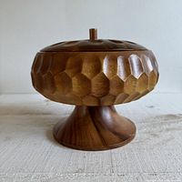 Side view of the carved wooden nut bowl on a pedestal base with lid.