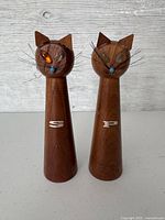 Front view of two wooden cat salt and pepper shakers showing gem eyes, letters S and P, and wire whiskers.