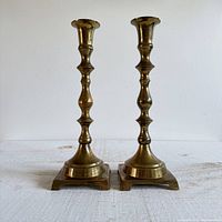 Front view of two brass candlestick holders showing their overall shape, size, and finish.