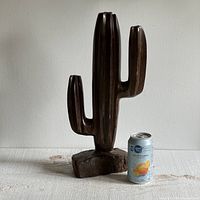 Front view of the hand carved ironwood cactus sculpture next to a soda can for scale, showing the overall shape, height, and base.