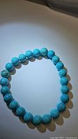 Top-down view of turquoise beaded stretchy bracelet showing round polished robin's egg blue beads with natural veining.