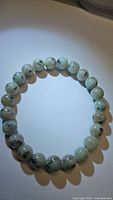 Front view of the natural Kiwi jasper bead bracelet showing pale green round beads with dark speckles.