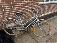 Side view of one retro bicycle with 26-inch wheels, metallic blue frame, black saddle, and tire with orange sidewall