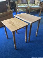 Two wooden side tables placed on blue carpet, showing relative size and details of legs and tops.