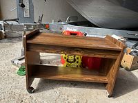 Rectangular wooden coffee table with two shelves placed on wheels shown in a garage or workshop area.