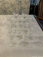 Full set of 12 flower-etched glasses arranged on table: 2 wine glasses, 5 after dinner drink glasses, 5 martini glasses.
