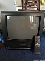 Black Panasonic CRT TV with built-in VHS VCR and FM radio. Remote control placed in front for scale and completeness.