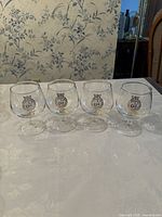 Photo of 4 snifter glasses with 1971 commemorative emblem placed on table.