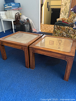 Photo of two matching vintage wooden coffee tables with glass tops over cane inlay, placed on carpeted floor.