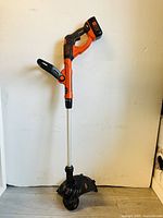 Full view of Black & Decker battery powered weed eater/lawn edger showing handle, shaft and cutting head.