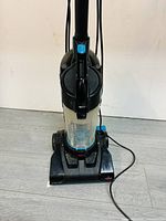 Front view of the Bissell PowerForce Compact vacuum showing the dust container and power base with cord.