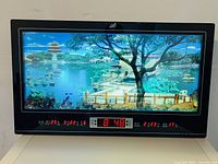 Front view of electronic wall calendar clock showing moving Chinese landscape, time, dates, and temperature