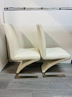 Side profile showing off-white leather, padded seat, backrest, and metal cantilever base