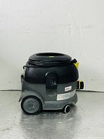 Front-side view of the Karcher Professional T12/1 vacuum cleaner showing coiled power cord and wheels.