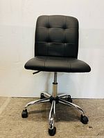 Front view of the black cushioned office chair showing seat, backrest, and chrome base with wheels.