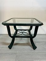 Side view of glass top side table showing curved legs and magazine holder below