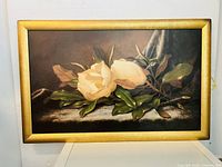 Front view of the framed floral painting showing white flowers and green leaves against a dark background.