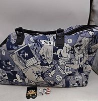 Front side view of Mickey Mouse cartoon print duffle bag with three trading pins displayed in front.
