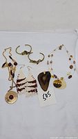 Photo showing the entire grouping of jewelry with five items including two cuff bracelets, two necklaces, and a pair of earrings.