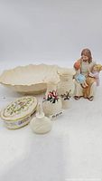 Overview of six Lenox porcelain pieces including a figurine of Jesus with children, two small vases with floral decoration, an oval floral trinket box, a cream-colored bowl, and a swan figurine.