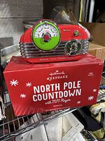The Hallmark North Pole Countdown MP3 player in original box, showing front and side views of the red retro-styled player.