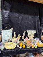 Full view of the Easter decorations set displayed on a black cloth backdrop, showing variety of figurines, plates, and eggs.