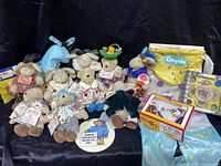 Overview of 13 Muffy Vanderbear collectible stuffed animals and various accessories including a large Crayola box and a blue donkey plush toy.