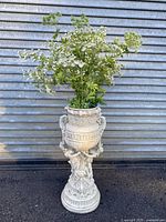Full front view of the cast plaster neoclassical plant stand with flowers inside and ornate detailing
