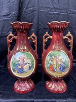 Pair of antique Austrian porcelain vases with hand-painted classical scenes and gold detailing on burgundy background.