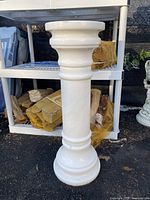 Full view of white marble column showing stacked classical design and base