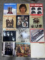 Top laid-out view of 12 Beatles and Wings Greatest vinyl LP albums showing full covers, varying conditions with wear and discoloration.