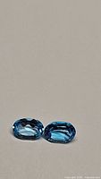 Pair of natural oval cut Swiss blue topaz gemstones, 1.78ct total, deep blue color, VS-VVS clarity, displayed on neutral background