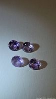 Four oval cut natural amethyst gemstones shown loose with purple color and transparency.