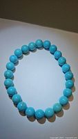 Photo showing the natural turquoise bracelet with polished round 8mm beads in robin's egg blue color, laid flat in a circular form against a light background.