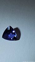 Trillion cut natural Tanzanite gemstone seen from the front showing deep blue-purple coloration and facets.