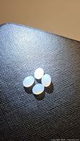 Four oval cabochon light-colored chalcedony gemstones arranged closely.