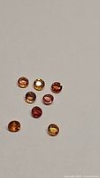 Eight round faceted multicolored sapphires on white background showing color range and clarity.
