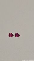 Two pear-shaped natural rubies on a neutral background showing their color and cuts.