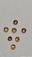 Seven natural round yellow sapphires arranged on a white background showing color and cut.