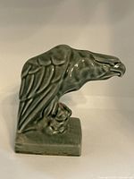 Side profile view of the glazed pottery eagle bookend showing detailed wing design and rectangular base.