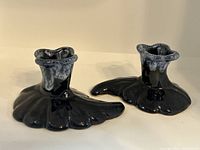 Pair of dark blue Anna Van Briggle candlesticks shown front view on white surface.