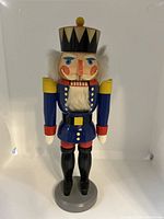Front view of painted wooden nutcracker figurine, showing detailed face, uniform and stance.