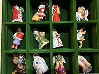 12 Franklin Mint Christmas ornaments displayed in a green compartment box, showing detailed figures dressed in traditional holiday attire