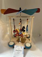 Full view of the carousel candle holder with three blue round tea light candle holders and hand-painted carousel horses with a four-blade propeller on top.