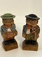 Front view of two hand-carved wooden folk art statues, one with an accordion and the other with a fiddle.