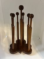 Front view of the wooden slipper holder featuring seven tall wooden pegs/hooks all mounted on a clover-shaped wooden base.