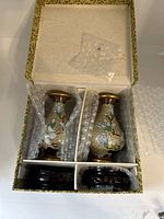 Top view of the open box containing two small cloisonné vases wrapped in bubble wrap and two carved wooden stands in separate compartments.